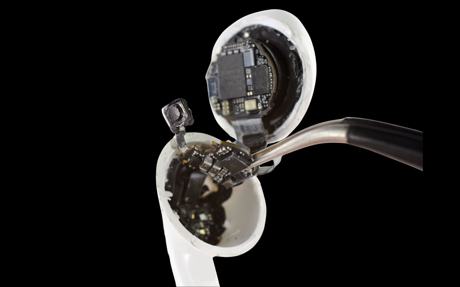 Detalhe técnico interno de AirPods com bateria e circuito